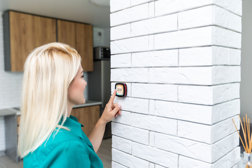 woman adjusting thermostat